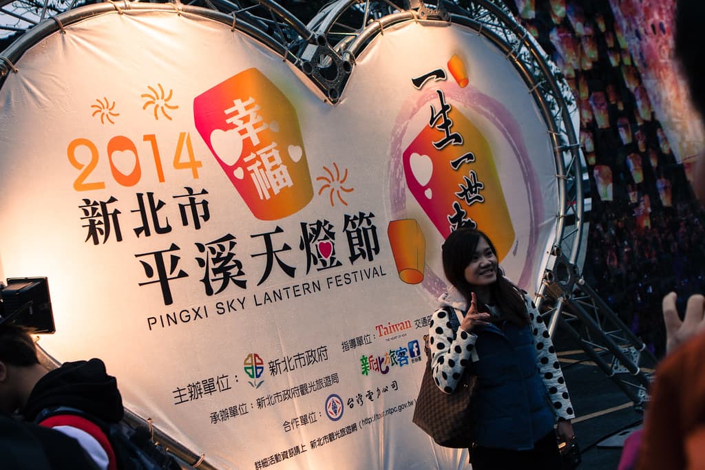 Visitors holding a large paper lantern while staff light it at Shifen Sky Lantern Square