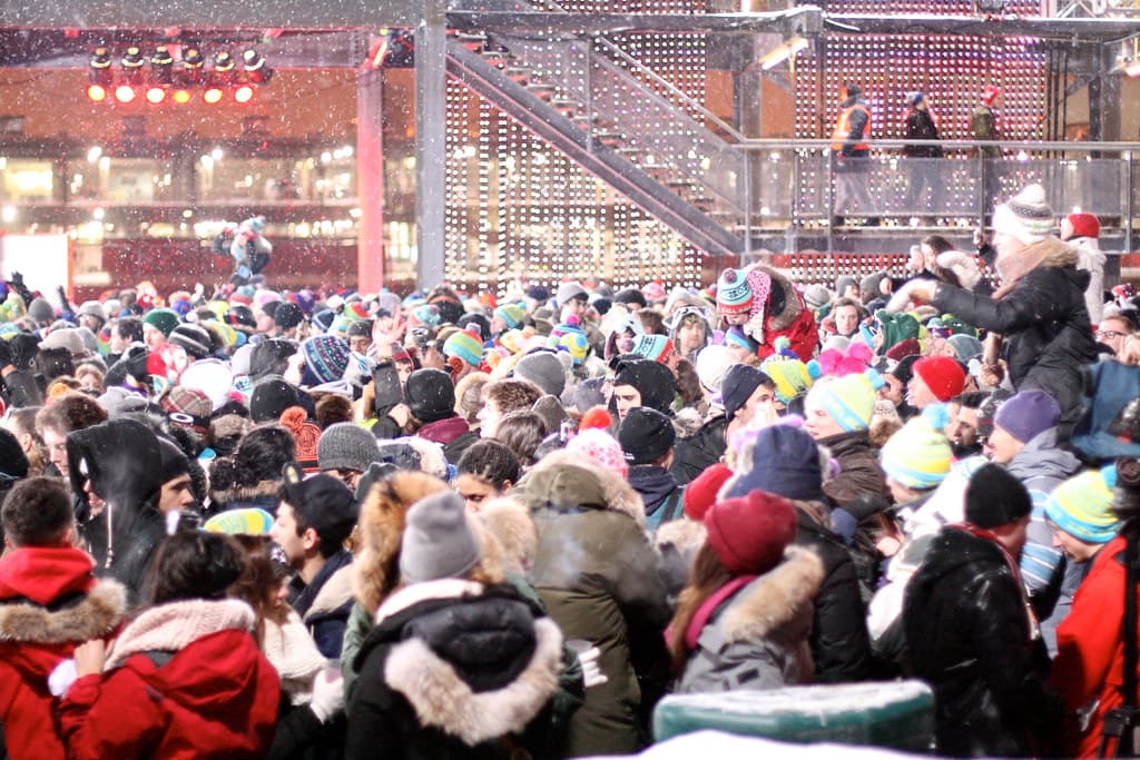 Group of friends in colourful parkas, balaclavas and snow pants dancing outdoors at Igloofest