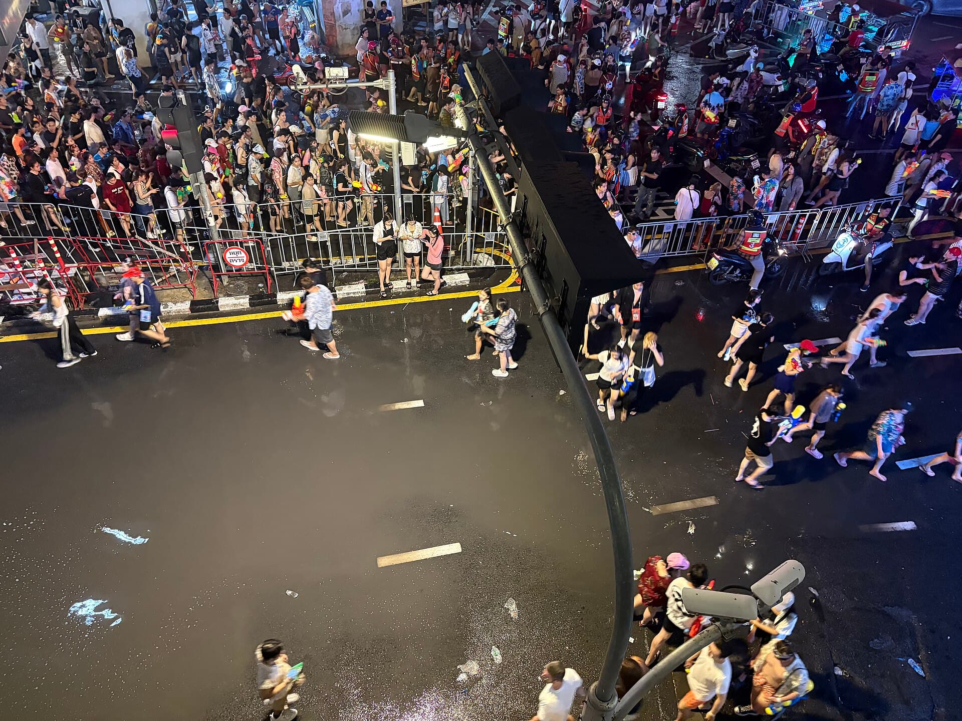 Water fight on Silom Road during Songkran with the BTS Skytrain track and Sala Daeng station overhead