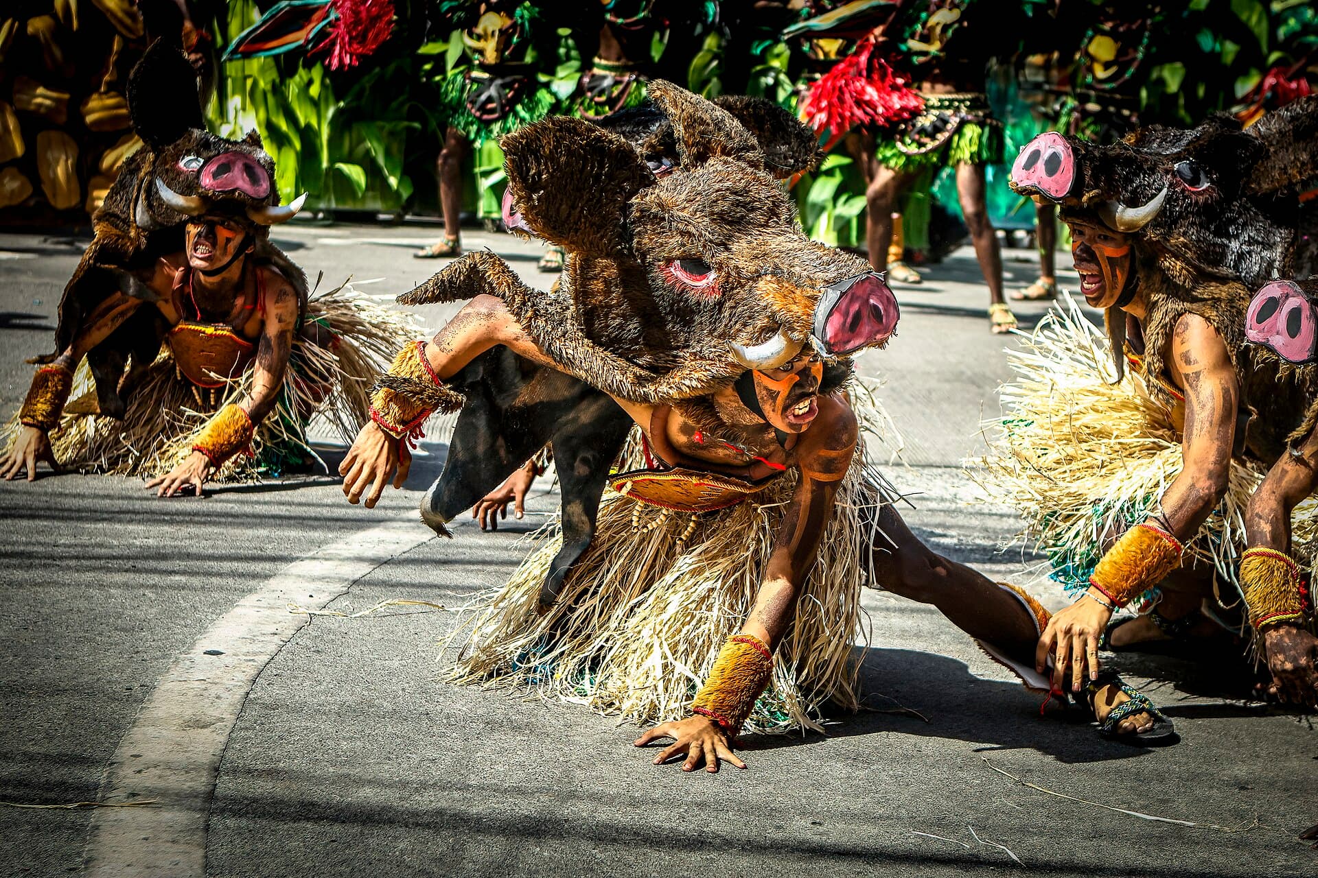 Wide shot of Dinagyang Ati tribe warriors in black body paint and feathered headdresses performing a formation in front of the Iloilo Freedom Grandstand, Iloilo City