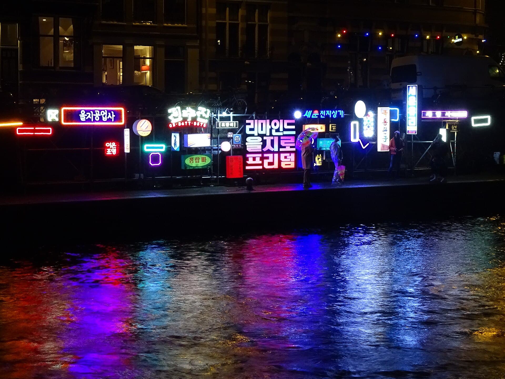 The Magere Brug lit up over the Amstel with visitors on the quay