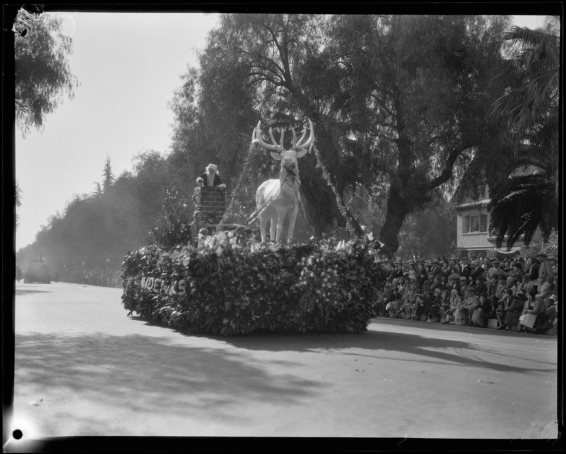 Floral floats moving along Colorado Boulevard in Pasadena during the Tournament of Roses Parade, wide landscape view with crowds on both sides