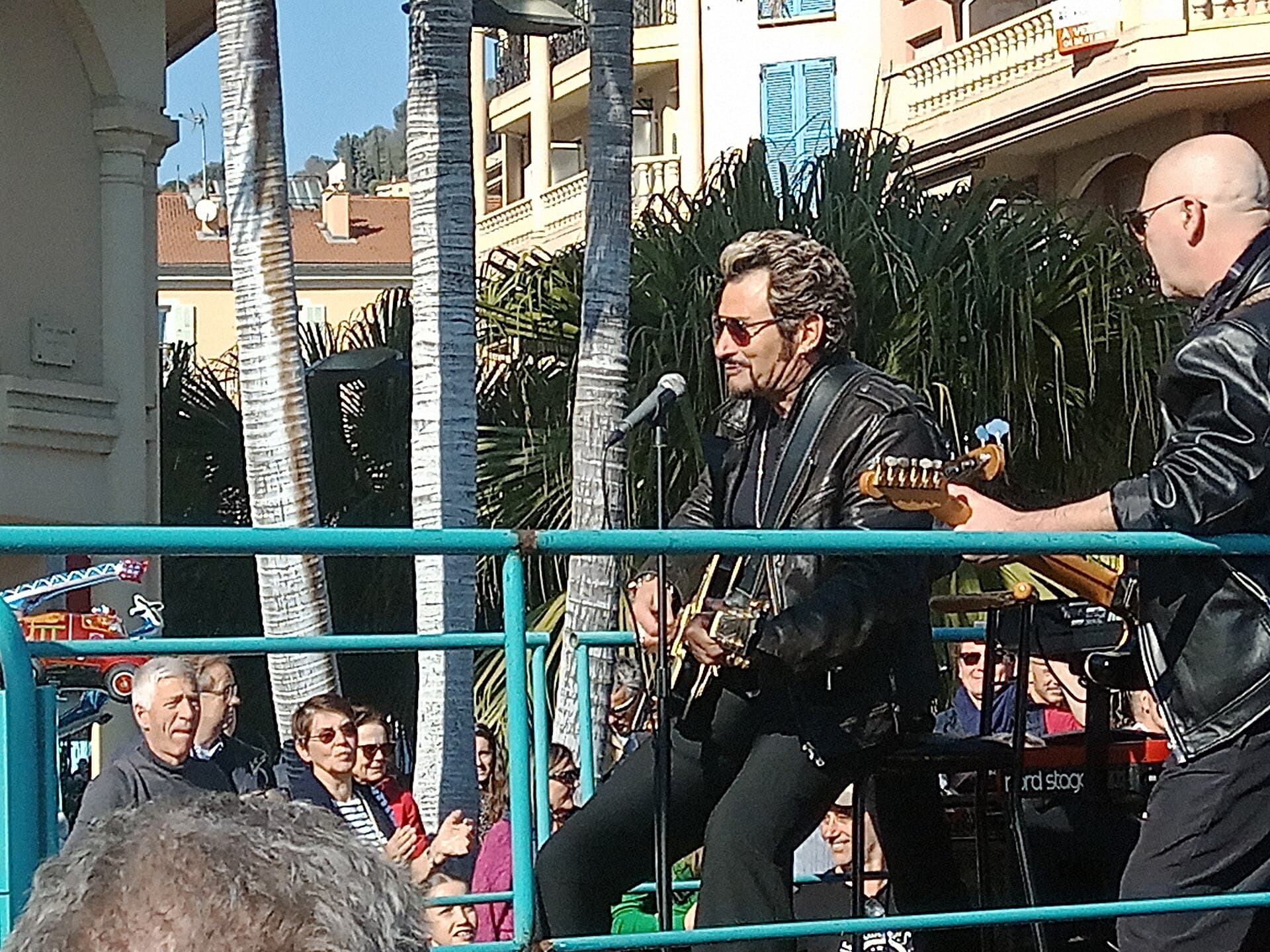 Crowd of spectators holding phones along the Promenade du Soleil in Menton during a corso