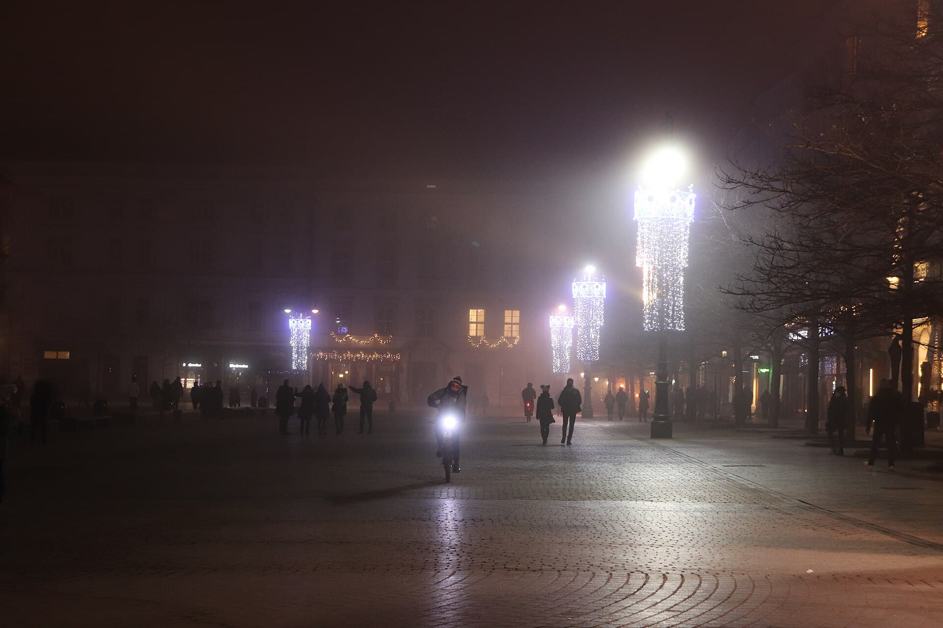 Carol singers on the stage on Rynek Glowny with the crowd in coats