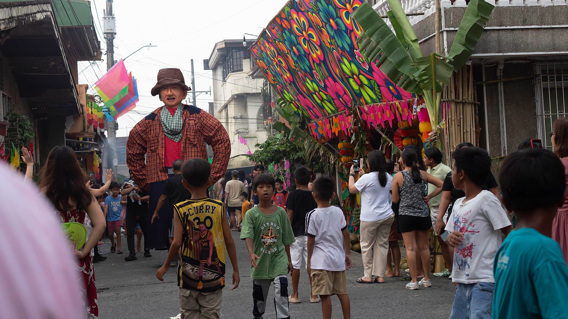 Visitors filming a higante with phones on M.L. Quezon Avenue, Angono