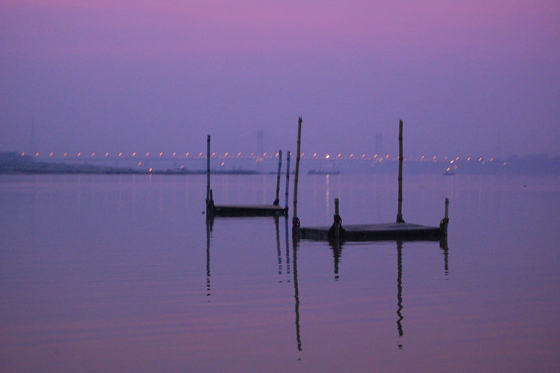 Wide view of the Triveni Sangam at Prayagraj, the confluence of the Ganga and Yamuna, with boats and bathers at Magh Mela