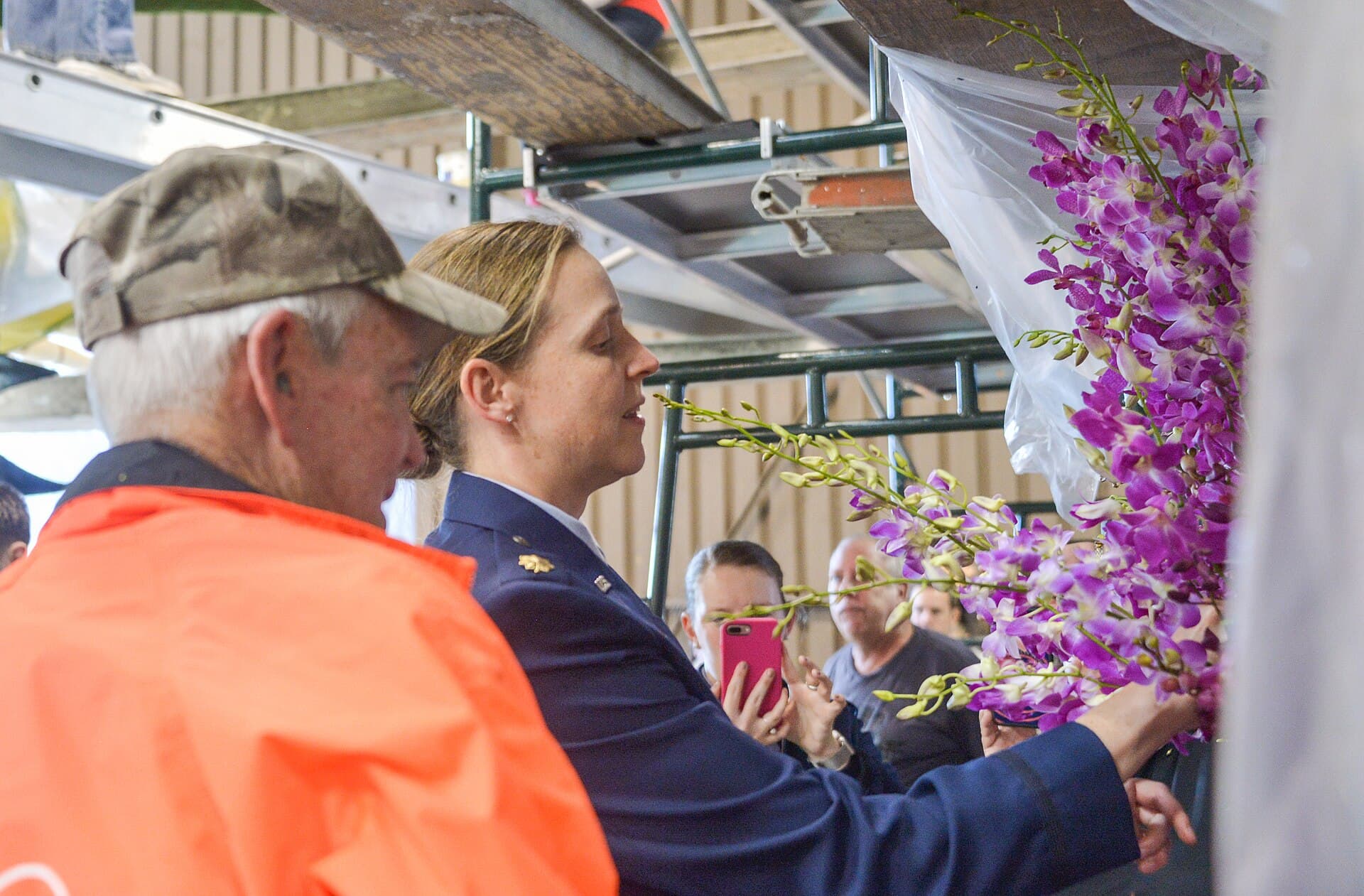 Volunteers gluing flower petals onto a Rose Parade float inside a decorating barn in Pasadena