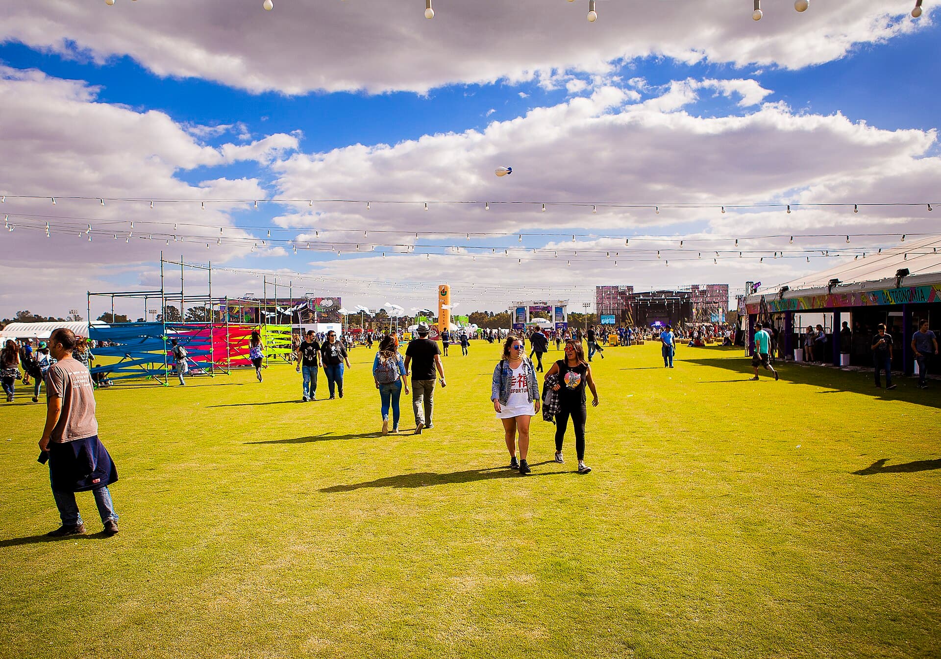 Wide shot of the crowd in front of a main stage at Lollapalooza Argentina at the Hipódromo de San Isidro in the late afternoon