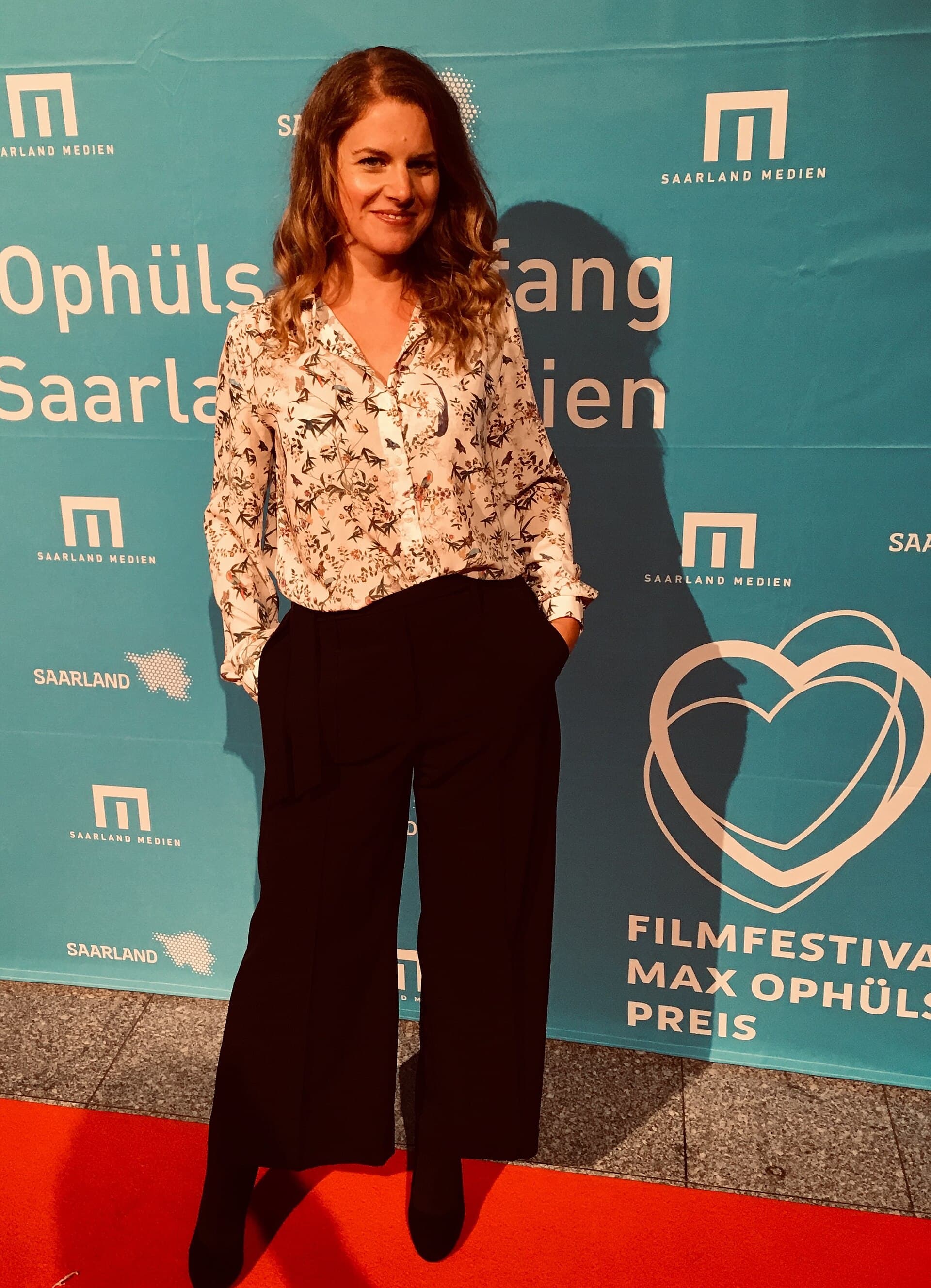 A festival visitor checking a Berlinale ticket QR code on a phone in front of a cinema entrance