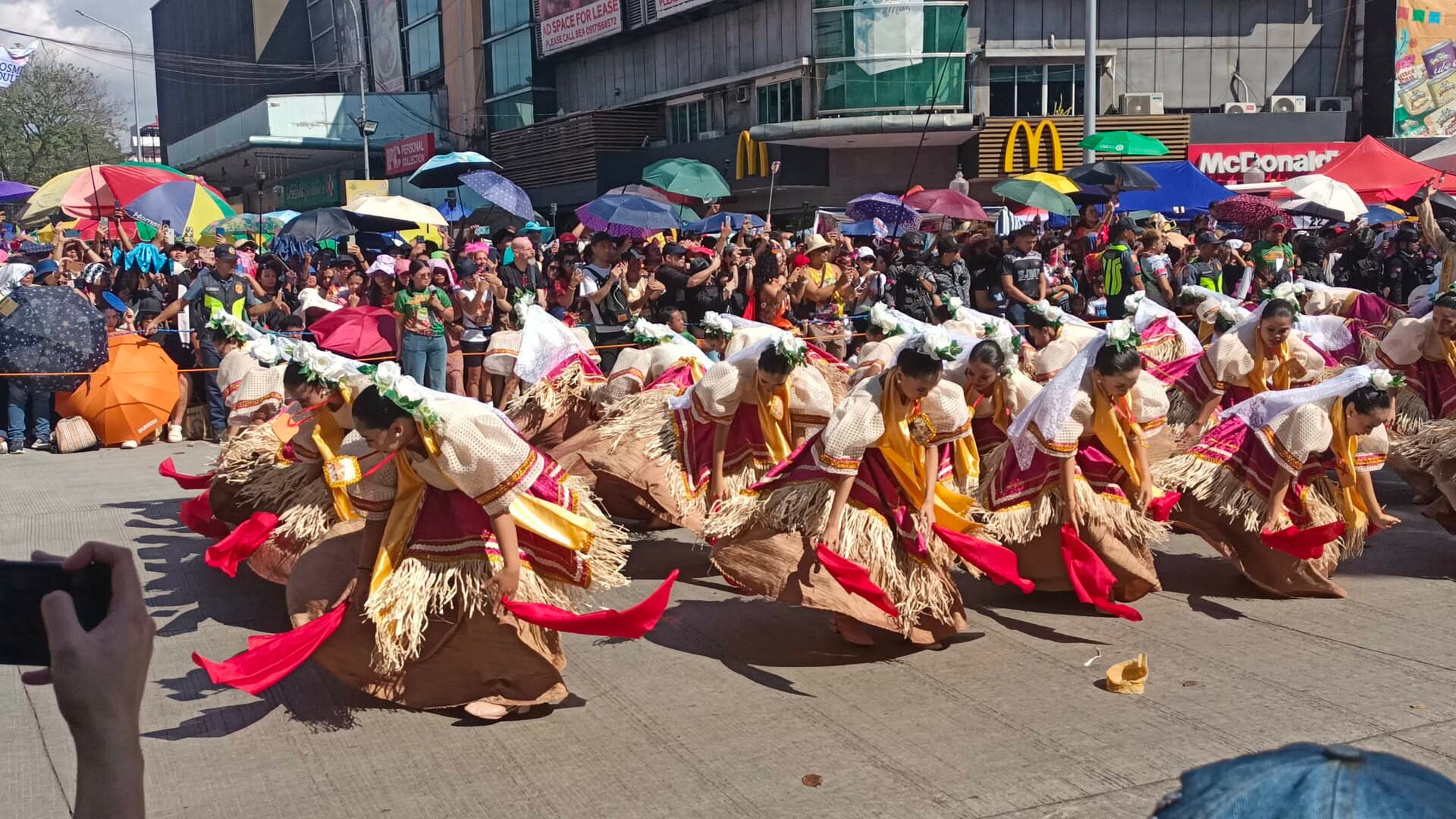 Crowds lining Osmeña Boulevard under a cloudy sky as a Sinulog contingent passes in Cebu City