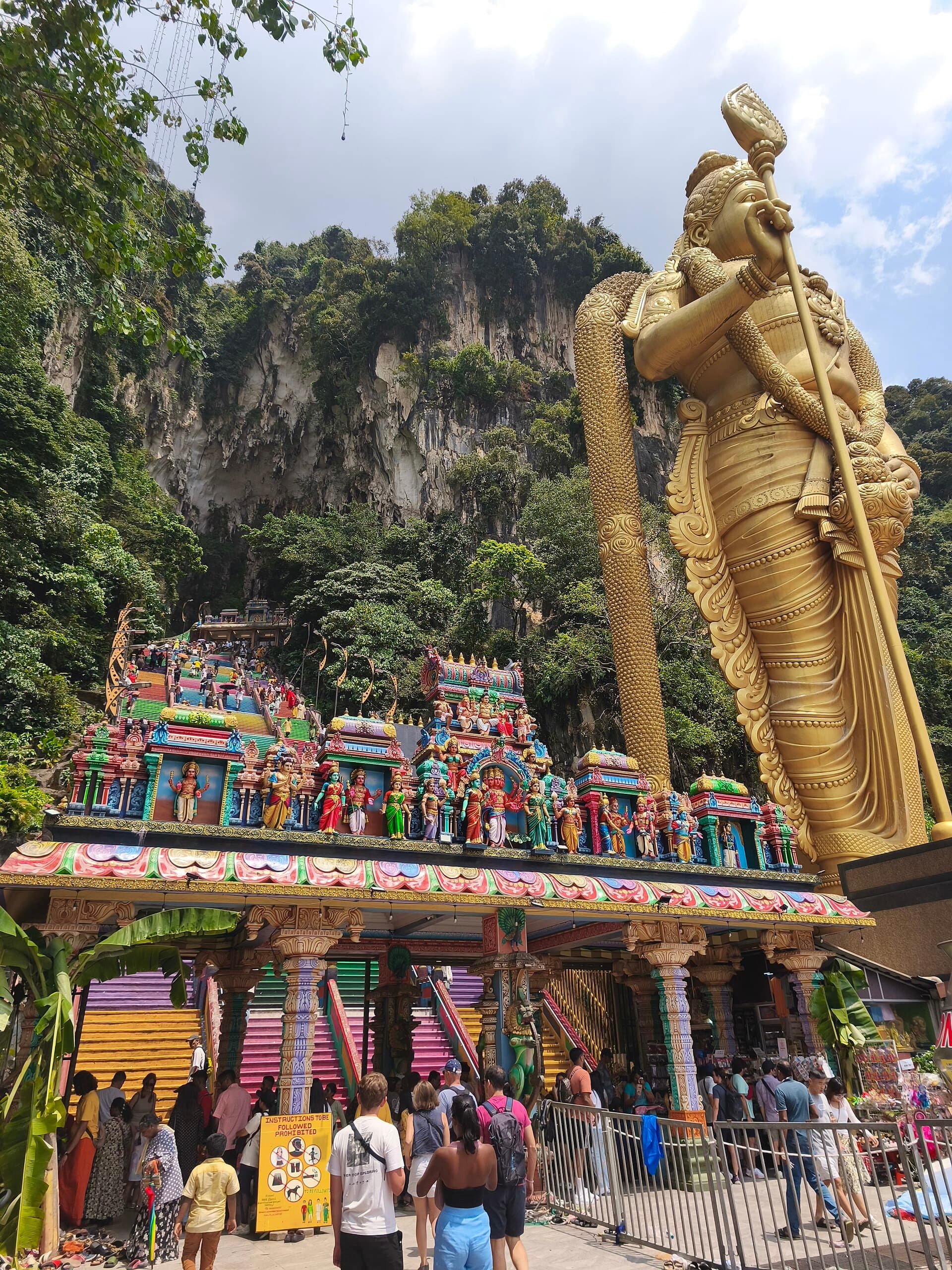 Devotees gathered in yellow and orange clothes at the foot of the Batu Caves steps at dawn