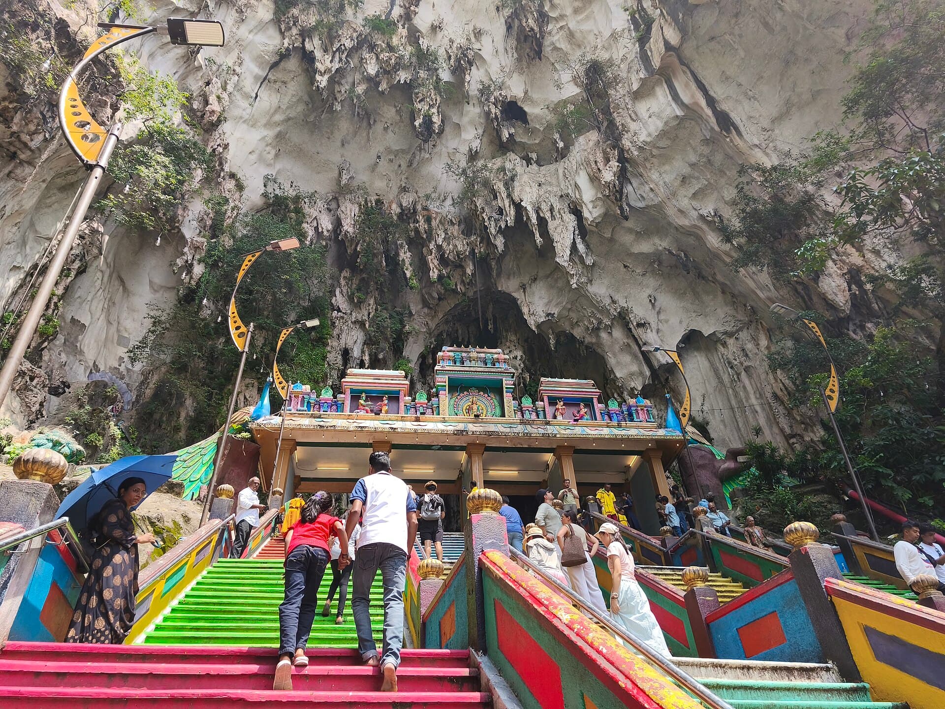 Visitors holding up phones at the base of the Batu Caves steps during the festival