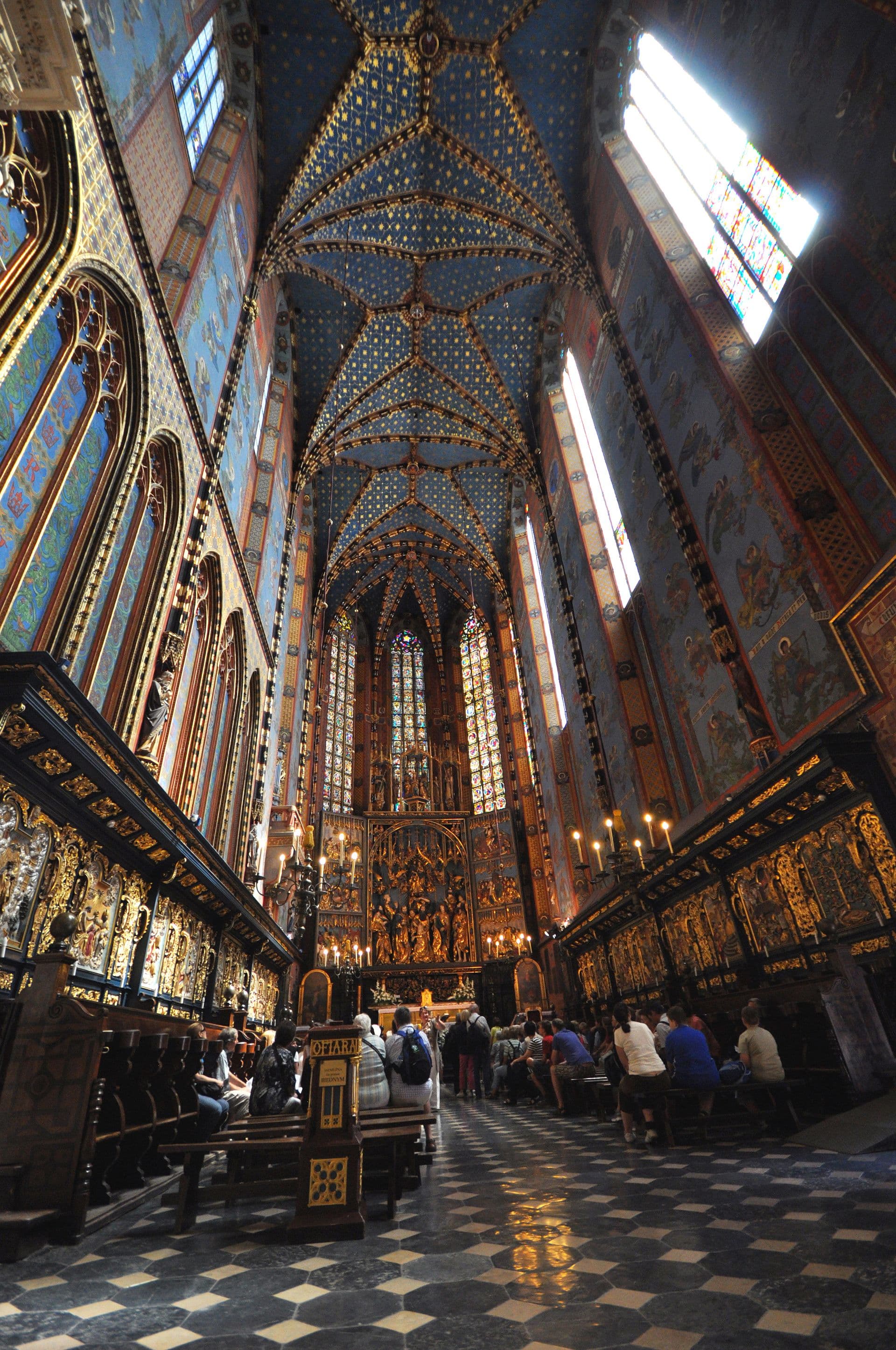 The Rynek Glowny Christmas tree and wooden stalls in front of the Cloth Hall at dusk