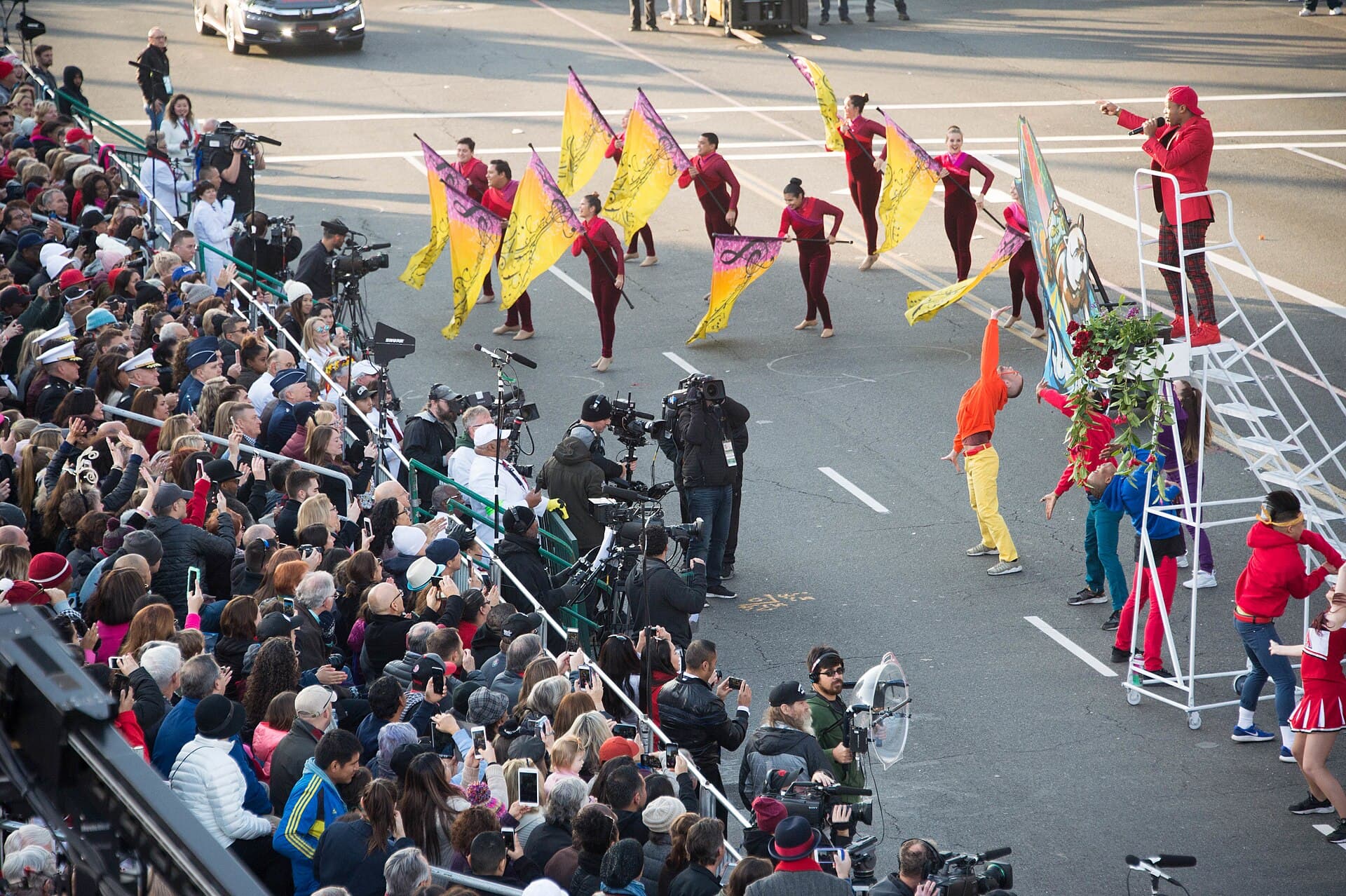 Spectators in a reserved grandstand on Colorado Boulevard watching a floral float pass during the Tournament of Roses Parade
