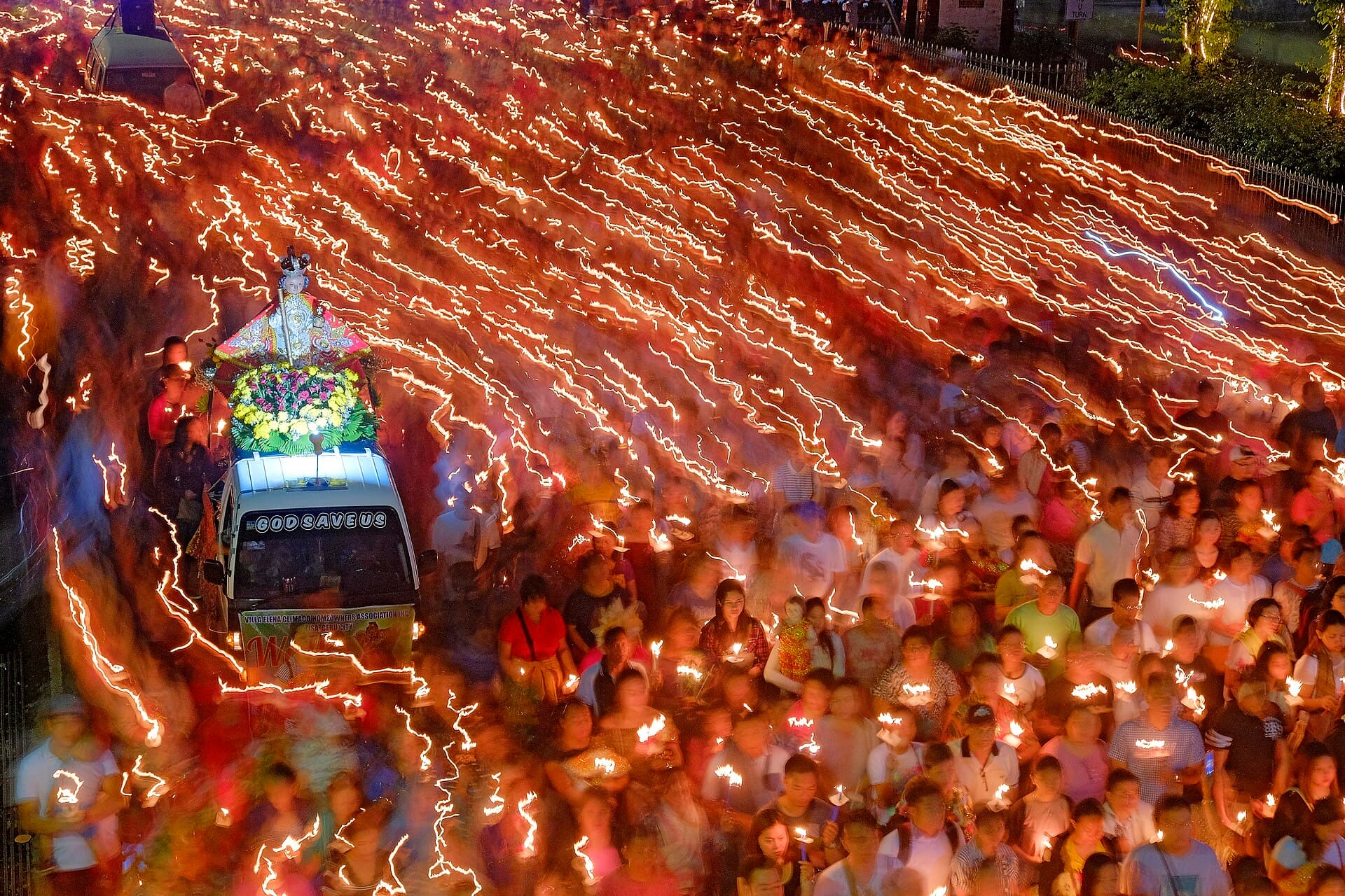 Devotees holding candles and Santo Niño images during the Solemn Foot Procession in Cebu City at dusk
