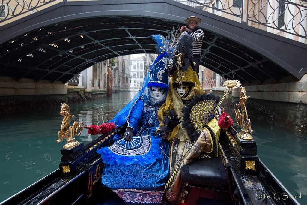 Costumed guests at a candlelit carnival dinner inside the frescoed halls of Ca' Vendramin Calergi on the Grand Canal