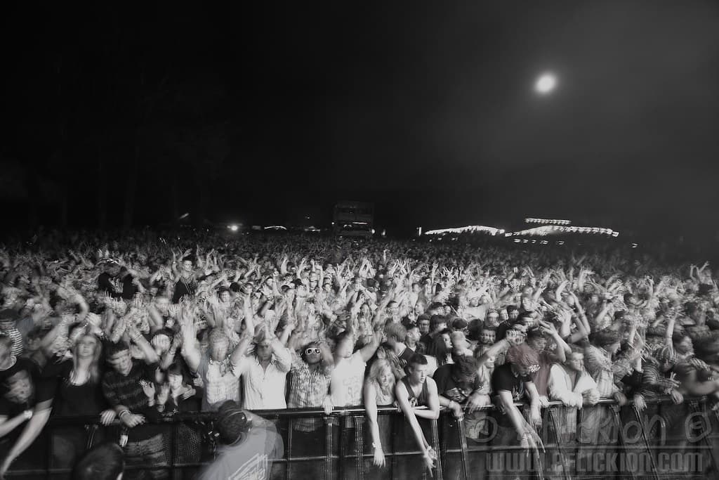 Crowd facing the main stage at Waiohika Estate at dusk, with the vineyard slope and hills behind