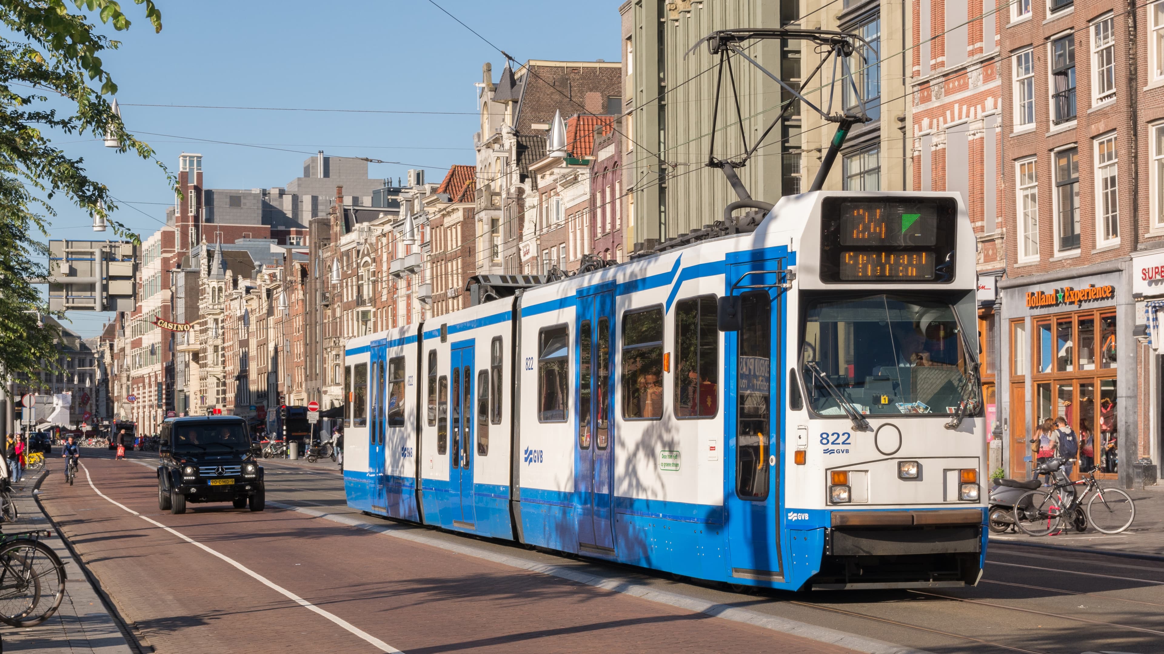 Amsterdam Centraal station facade at dusk with tram stops in front and the Damrak canal beside it