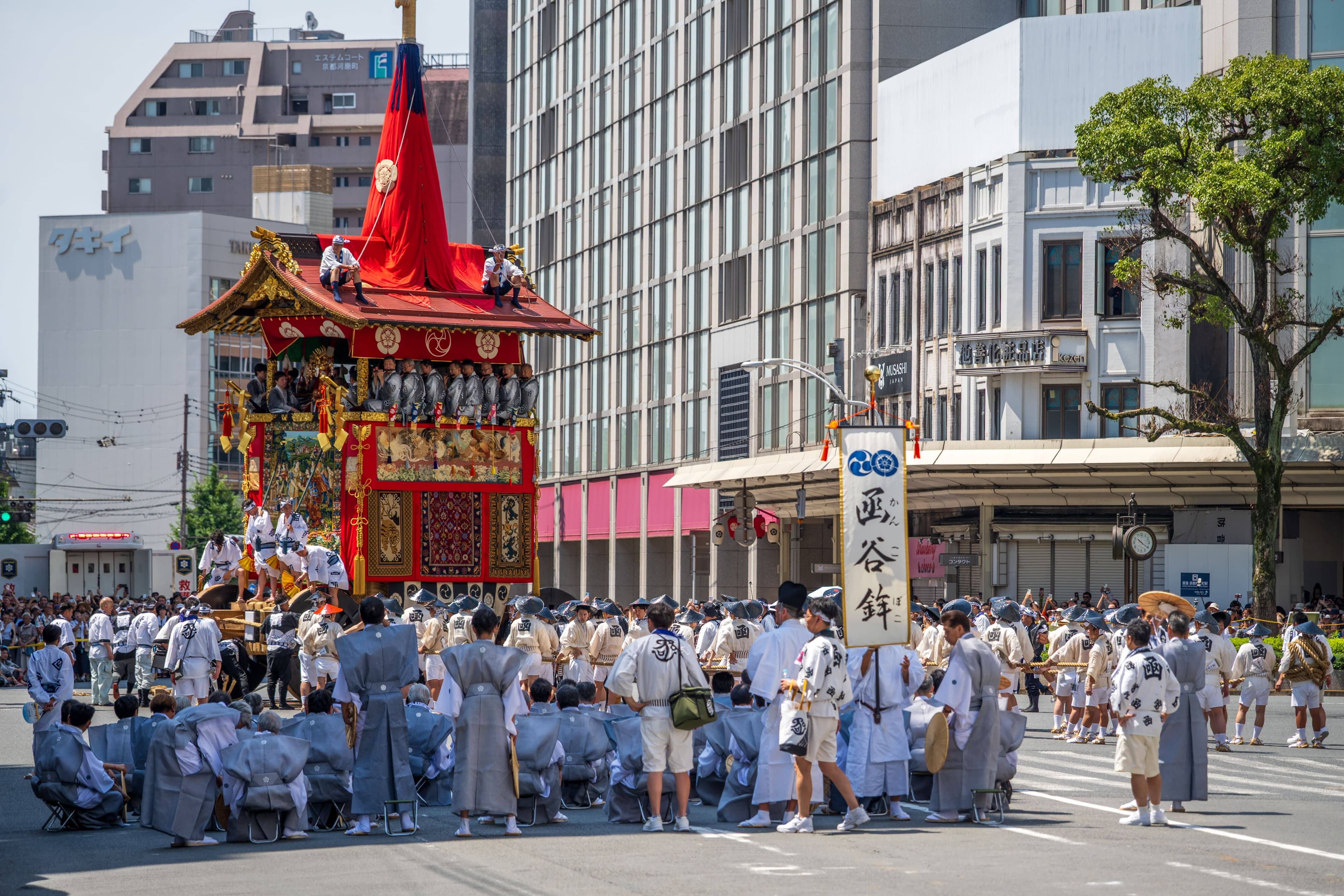The Shijo-Karasuma intersection in central Kyoto with the Hankyu Karasuma station entrance and a yamaboko float standing in the street during Yoiyama