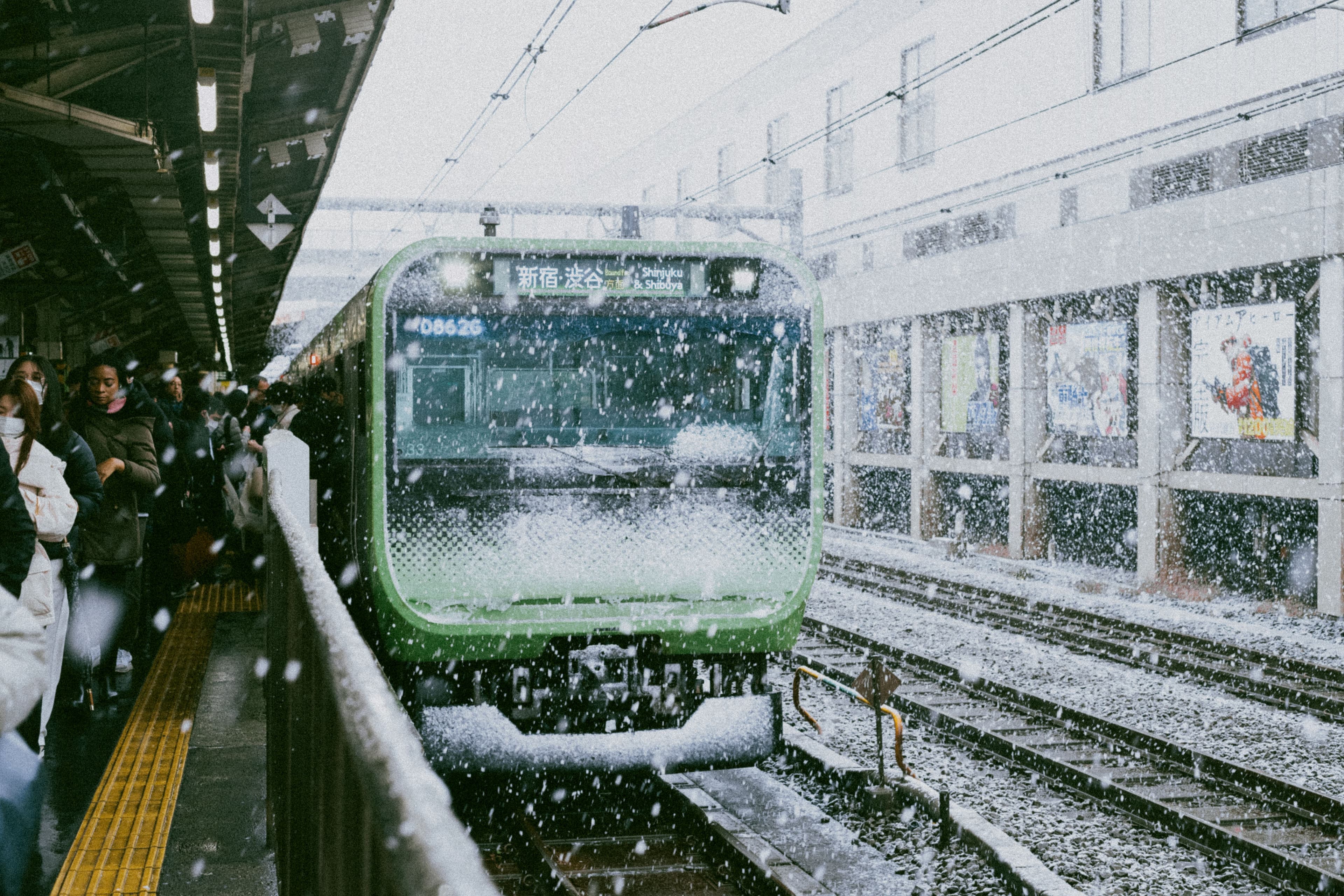 The entrance of Odori subway station in central Sapporo in winter with snow piled on the pavement and the Sapporo TV Tower visible in the background