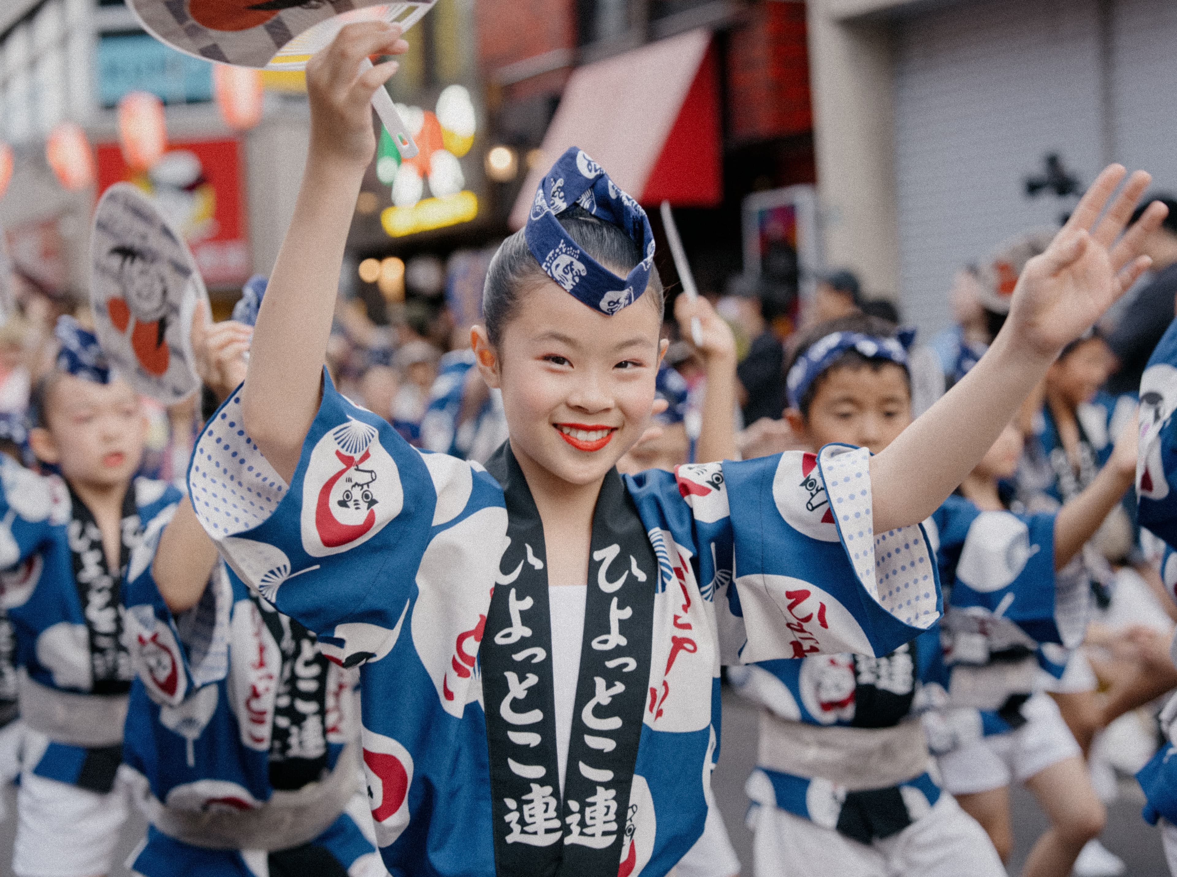 Reserved tiered seating along a Tokushima street stage filled with spectators watching Awa Odori dancers pass at night