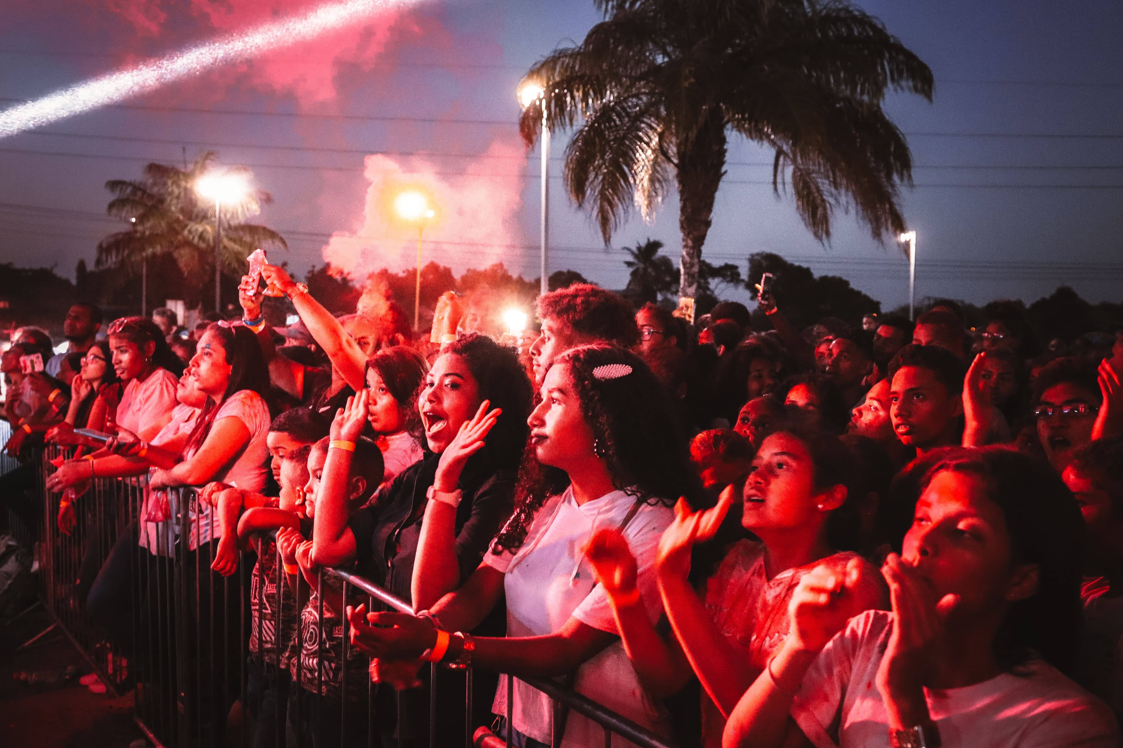 Festival-goers in light outfits and hats walking into EDC Orlando in late-afternoon sun at Tinker Field