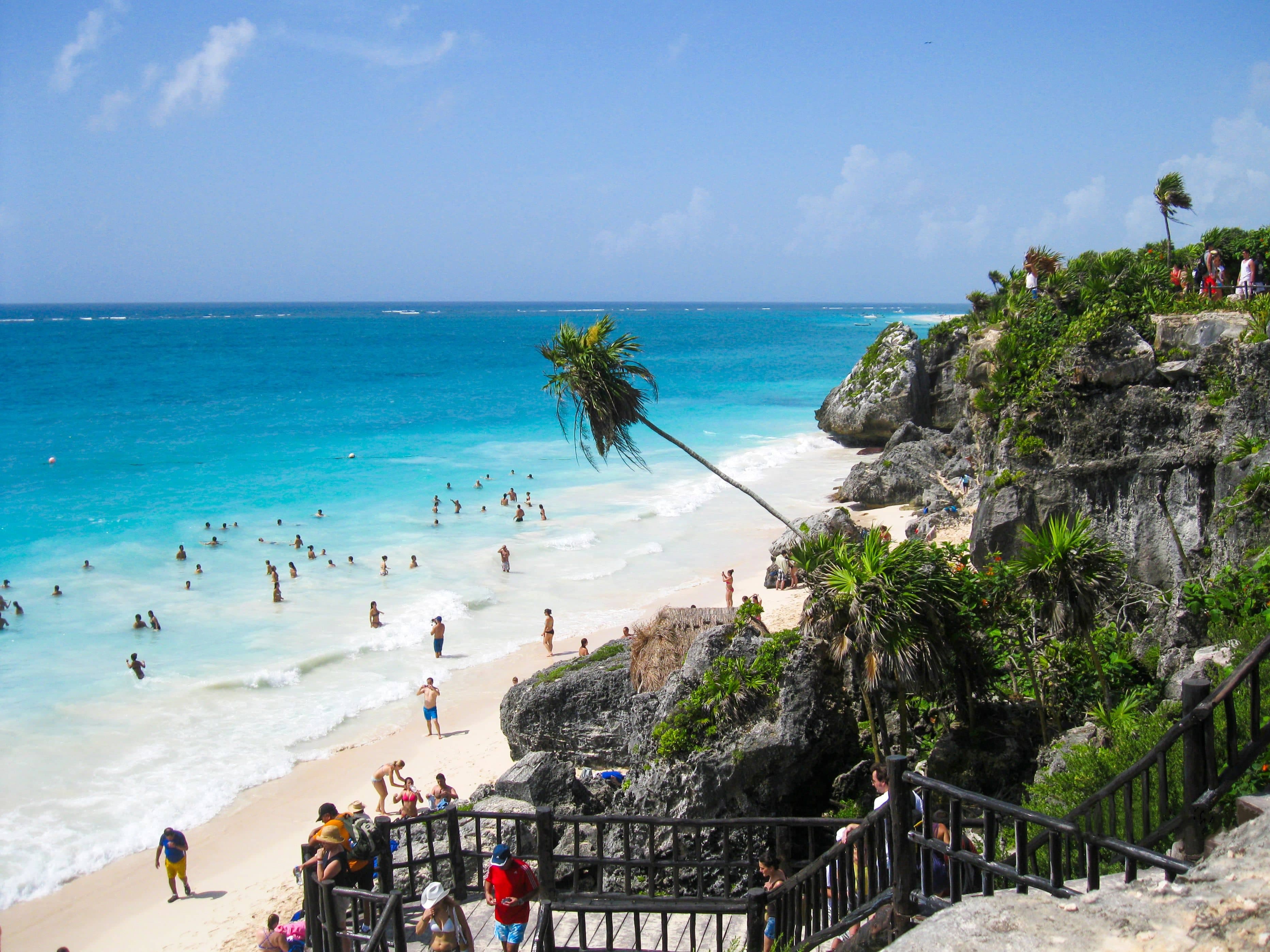 Tulum beach at midday in January with turquoise sea and palm trees